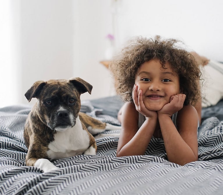 un enfant et un chien couchés sur un lit regardant la caméra