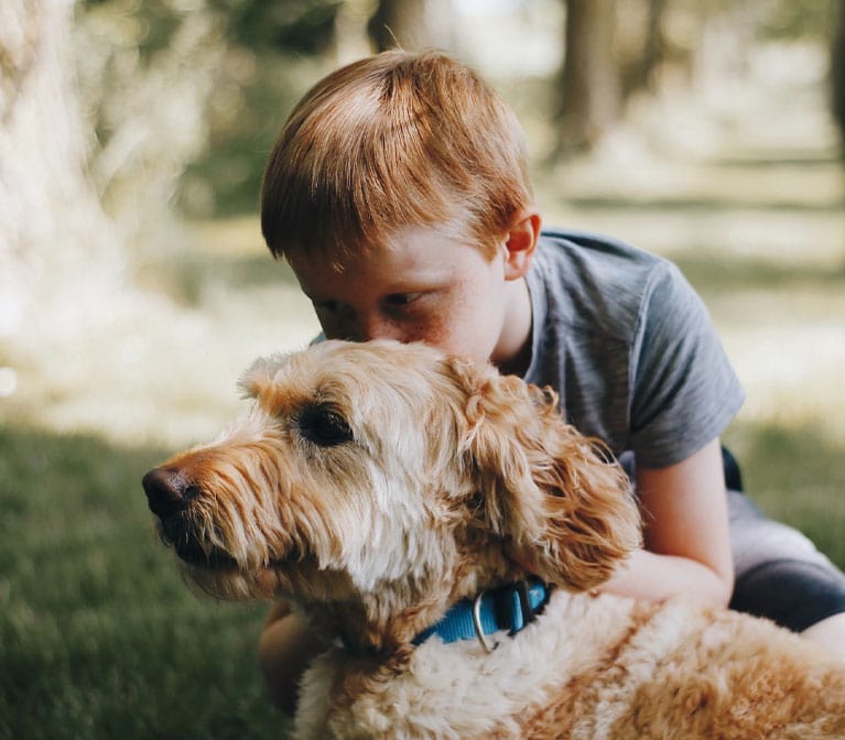 Petit garçon qui donne un bisou à un son chien beige