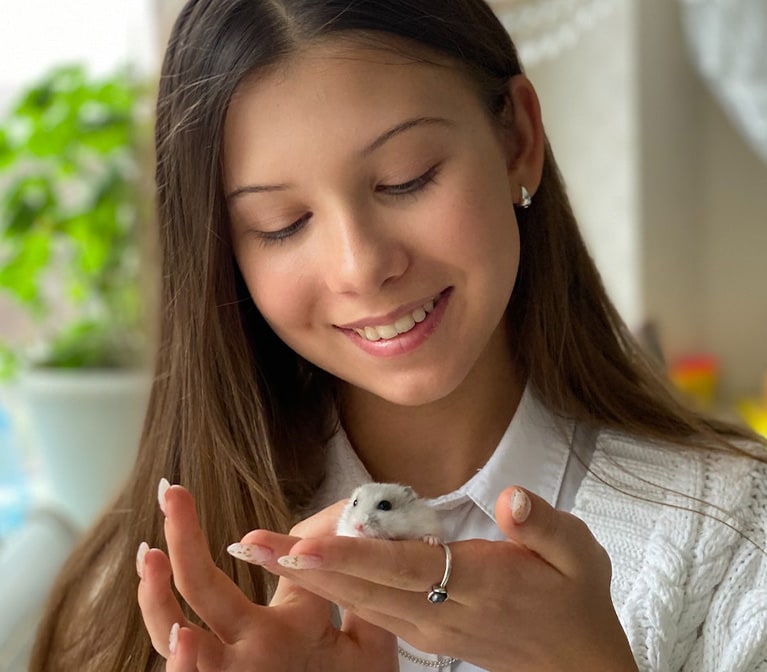 Jeune fille qui flatte un hamster dans sa main